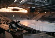 A pair of ice skates on a bench overlooking a blurred college ice rink.