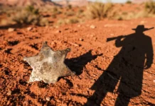 A conceptual image of a lawman's badge in desert sand.